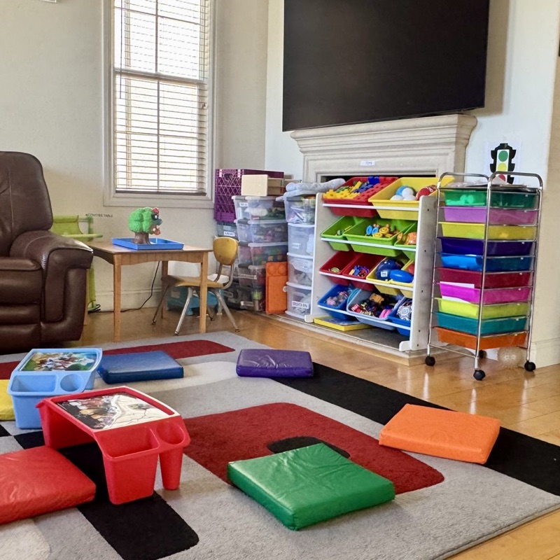 Rainbow toy organizer bins and a rolling rainbow drawer cart brimming with craft supplies, near a bright window